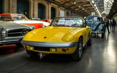 Gelber Lotus Elan Sprint, Baujahr 1972, mit dem Kennzeichen 07. Daneben ein Mercedes-Benz und ein VW Käfer.