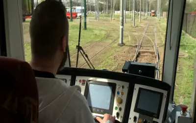 Mężczyzna za sterami tramwaju, być może uczestnik darmowego kursu na maszynistę, obserwuje tory.
