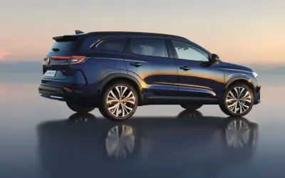 Granatowy Renault Espace 2024 z odbiciem na wodzie, na tle zachodzącego słońca.