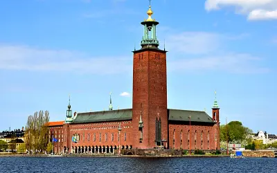 Stockholms stadshus reser sig stolt vid vattnet, dess ikoniska torn dominerar horisonten.