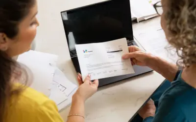 Dwie kobiety analizują dokumenty, szukając rozwiązania, być może ostatniego kredytu dla zadłużonych.