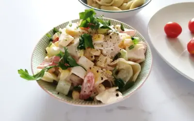 Pyszna sałatka z tortellini, jajka, kukurydzy i pomidorów, udekorowana natką pietruszki.