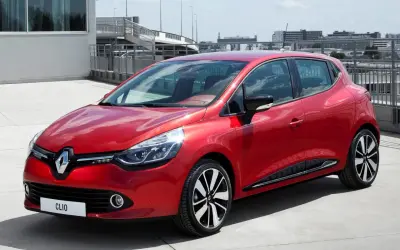 Czerwone Clio 4 RS błyszczy na betonie, gotowe do dynamicznej jazdy.