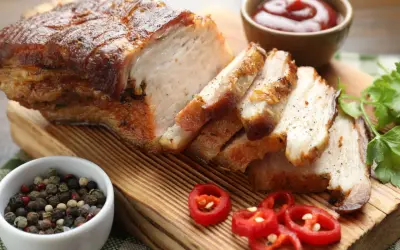 Pyszny boczek pieczony według przepisu babci Stasi, pokrojony w plastry, z dodatkiem pieprzu, chili i sosu.