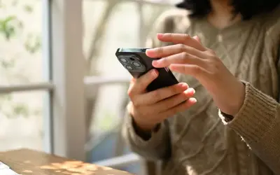 Dłonie kobiety trzymają smartfon, korzystając z aplikacji do zdjęć paszportowych.
