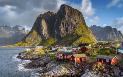 Traumhafte norwegen route 2 wochen: Rote Fischerhäuser am Fuße steiler Berge an der Küste.