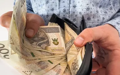 Ręce trzymają portfel z banknotami 200 zł. To symbol nagrody jubileuszowej za 40 lat pracy w budżetówce.