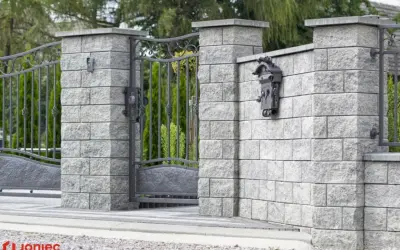Betonowy słupek z zamontowaną skrzynką na listy i fragmentem metalowej furtki.