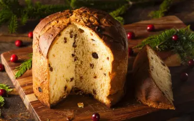 Ein köstlicher Panettone, perfekt für ein sizilianisches Panettone Rezept, mit Rosinen und Nüssen, dekoriert mit Cranberries und Tannenzweigen.