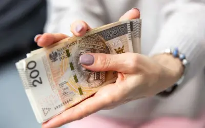 Dłonie trzymające plik banknotów 200 zł.