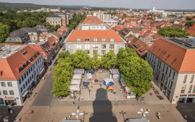 Marktplatz in Erlangen mit Ständen und Bäumen. Ein Schatten wirft sich über den Platz, vielleicht ein Geheimtipp für Fotografen.