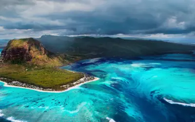 Podwodny wodospad w **Oceania** przy Le Morne Brabant, Mauritius. Turkusowa woda, góra i chmury.