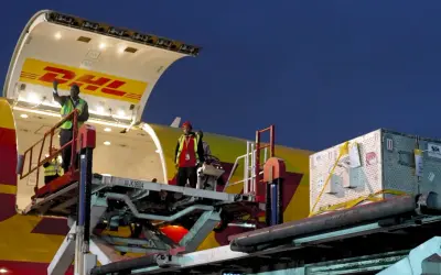 Pracownicy rozładowują samolot DHL. Z jakiego kraju pochodzi ten transport?