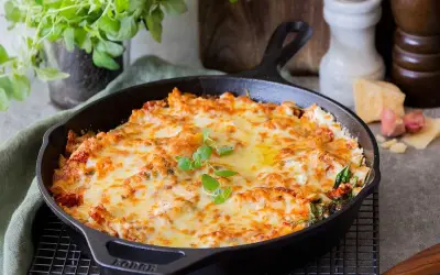 En gyllene, bubblande vegetarisk lasagne i gjutjärnspanna, toppad med färska örter. Perfekt för en mysig middag.