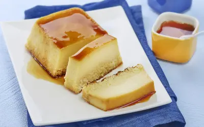 Un délicieux flan au lait concentré, parfait pour une recette flan lait concentré Nestlé. Servi sur une assiette blanche avec un coulis de caramel.