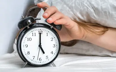 Ręka wyłącza budzik. Jest 5:00, a 0303 znaczenie tego czasu to nowy początek dnia.