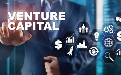 Biznesmen wskazuje na ekran z napisem VENTURE CAPITAL i ikonami symbolizującymi rozwój, pieniądze i innowacje.