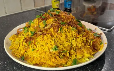 En stor portion gyllene biryani med kyckling, toppad med krispig lök och färsk koriander. Ett perfekt biryani recept för en festmåltid.