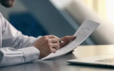 Mężczyzna w białej koszuli analizuje dokument, sprawdzając warunki, kiedy pracodawca nie musi wypłacić odprawy.