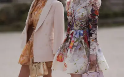 Jasny żakiet do sukienki w kwiaty to świetny wybór. Dwie kobiety prezentują stylizacje z kwiecistymi sukienkami i eleganckimi torebkami.