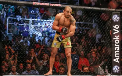 Jose Aldo, en ikonisk MMA-fighter, står i buren, redo att utöka sitt imponerande jose aldo record. Publiken jublar bakom nätet.