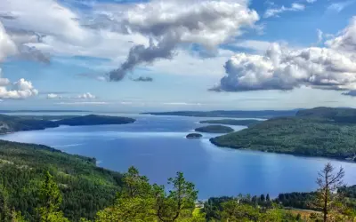 Vacker utsikt över en sjö med öar, omgiven av skogklädda berg. Ett perfekt ställe att uppleva Stockholms naturreservat.