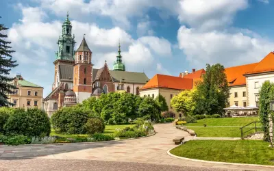 Wawel cennik: malowniczy widok na zamek i katedrę z zielonymi ogrodami i brukowanymi alejkami.