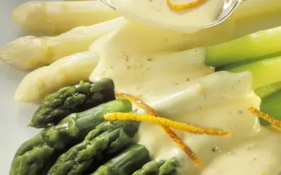 Frischer Spargel, weiß und grün, wird mit einer cremigen Sauce und Orangenzesten serviert. Perfekt zum Spargel kochen.