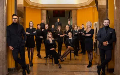 Grupa profesjonalistów w czarnych strojach pozuje w eleganckim wnętrzu.