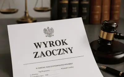 Dokument z napisem "WYROK ZAOCZNY" leży obok młotka sędziowskiego i wagi sprawiedliwości.