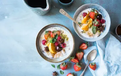 Dwa talerze owsianki z owocami (truskawki, maliny, pomarańcza, marakuja) i gwiazdkami anyżu. Idealne na śniadanie w stylu dieta wysokowęglowodanowa.