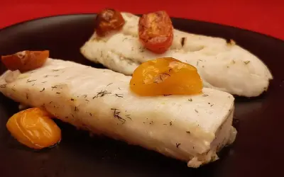 Deux pavés de dos de merlu tendres, parsemés d'aneth et surmontés de tomates cerises rôties, sur une assiette noire.