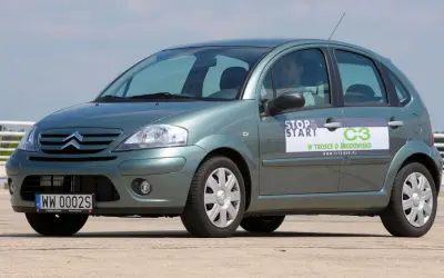 Zielony Citroen C3 z naklejką "Stop & Start" i informacją "W trosce o środowisko". Widać przednie żarówki.