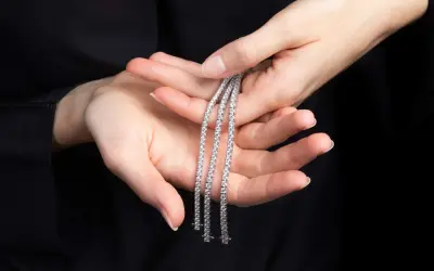 Mani delicate tengono tre scintillanti bracciali tennis, un classico intramontabile la cui storia affonda le radici nel mondo dello sport.
