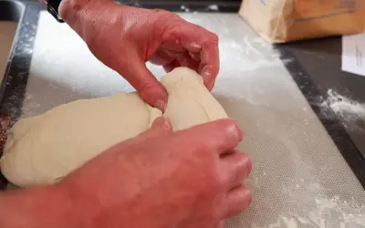 Mains travaillant la pâte à pain, étape d'autolyse. La pâte est souple et prête à être façonnée.