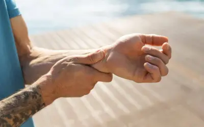 Mann hält sich das Handgelenk, da er Handgelenk schmerzen hat.