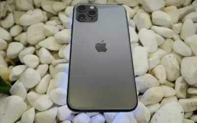 Szary iPhone 11 Pro leży na białych kamieniach. To urządzenie iPhone niedostępne, ale wciąż piękne.