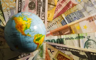 Globus na tle różnych walut. Czy na Malcie można płacić dolarami? To pytanie zadaje sobie wielu podróżnych.