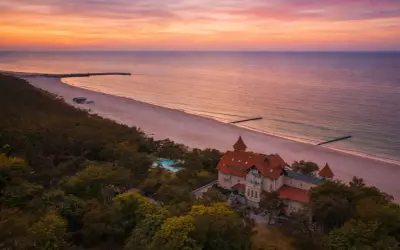 Piękny zachód słońca nad morzem, z widokiem na hotel i plażę. Idealne miejsce, by zastanowić się, gdzie na wakacje.