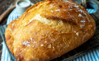 Ein frisch gebackenes, knuspriges Brot liegt auf einem Holzbrett. Perfekt für einfaches Brot backen.