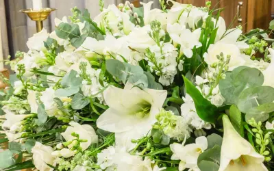 Piękna, biała wiązanka kwiatów z liliami, różami i zielonymi liśćmi.
