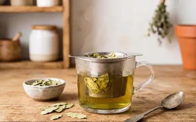 Infusion de feuille de séné, danger potentiel pour la santé. Une tasse de thé fumant avec des feuilles dans un infuseur, à côté d'un bol de feuilles séchées et d'une cuillère.