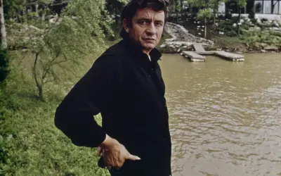 Johnny Cash, w czerni, stoi nad wodą. W jego oczach widać ból, jakby przeżywał coś trudnego, jak w piosence "Hurt".