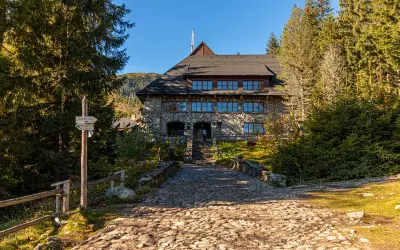 Kamienny schronisko w Dolinie Chochołowskiej, z brukowanym podejściem i drogowskazem.