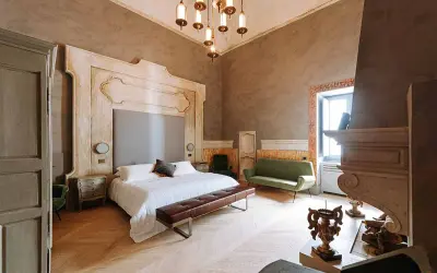 Ett lyxigt sovrum med en stor säng, grön soffa och en imponerande eldstad. Perfekt hotell inredning inspiration för ett elegant hem.