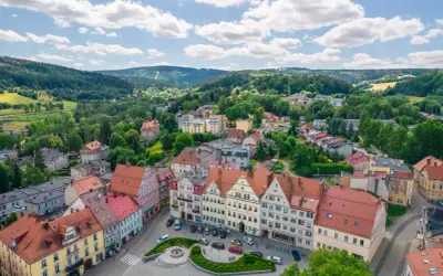 Urokliwy rynek w Dusznikach Zdroju z kolorowymi kamieniczkami i zielenią.