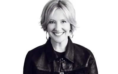 Uśmiechnięta Brené Brown w skórzanej kurtce, uosobienie odwagi i autentyczności.