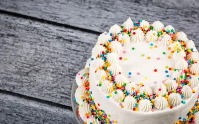 Torta bianca decorata con panna e confettini colorati, un esempio di torte di compleanno particolari per una festa allegra.