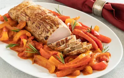 Un arrosto di maiale affettato, servito con peperoni e carote in salsa, un piatto di secondi di carne sfiziosi al forno.