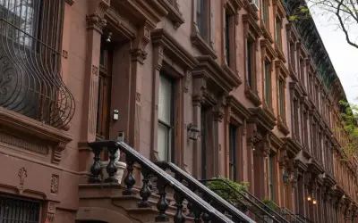 Brązowe kamienice w stylu brownstone, typowe dla Harlem, Nowy Jork, z ozdobnymi detalami i schodami.